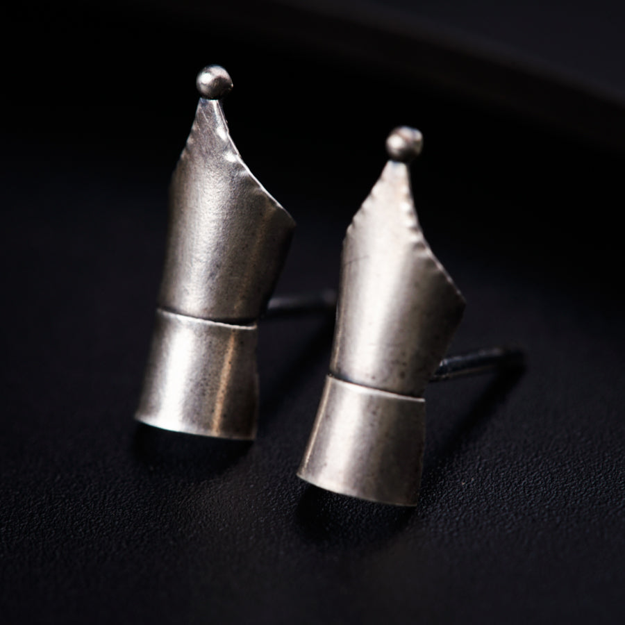 a pair of silver earrings sitting on top of a table