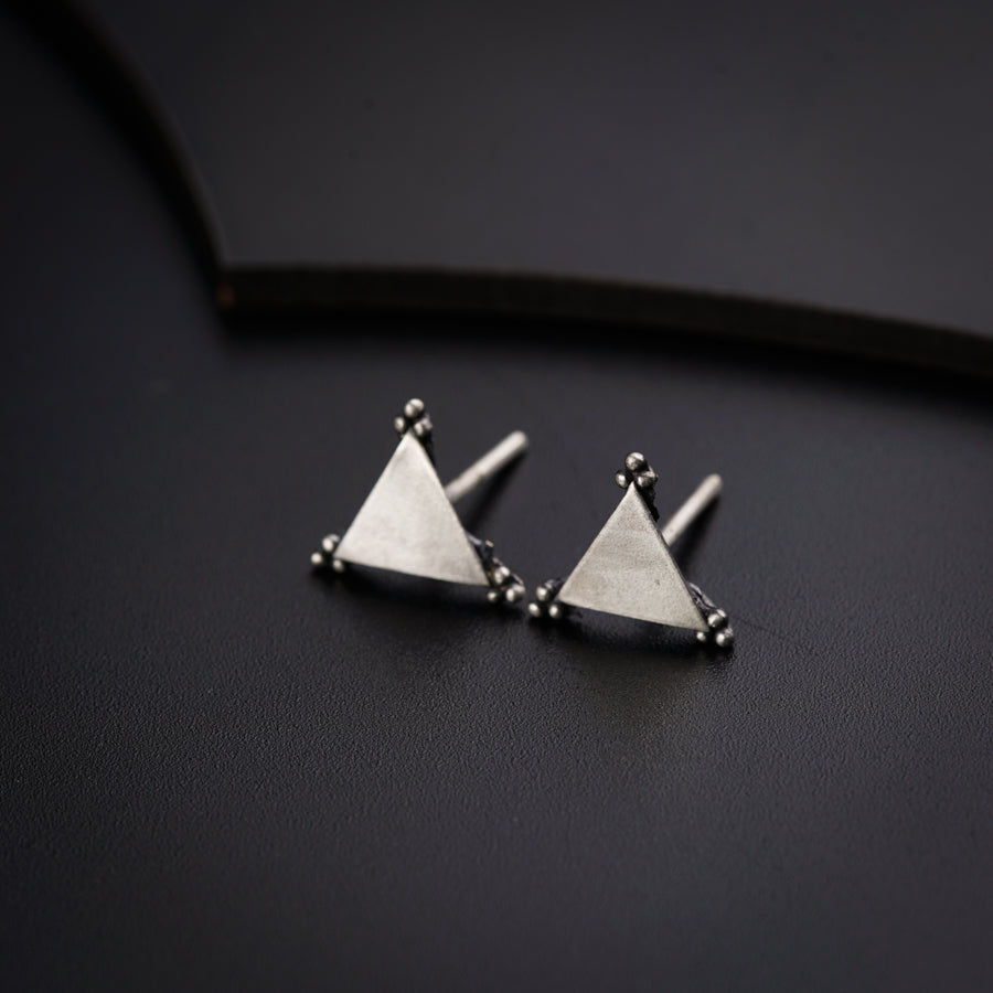 a pair of triangle shaped studs on a black surface