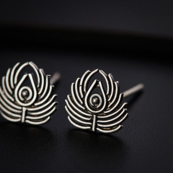 a pair of silver earrings on a black surface