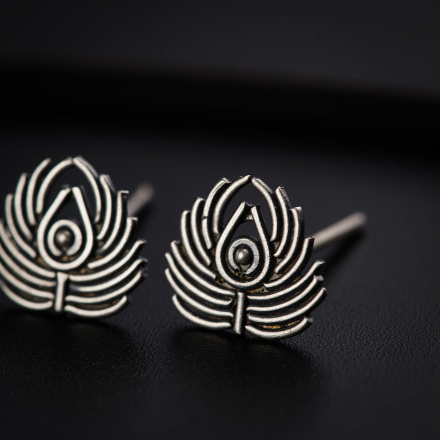 a pair of silver earrings on a black surface
