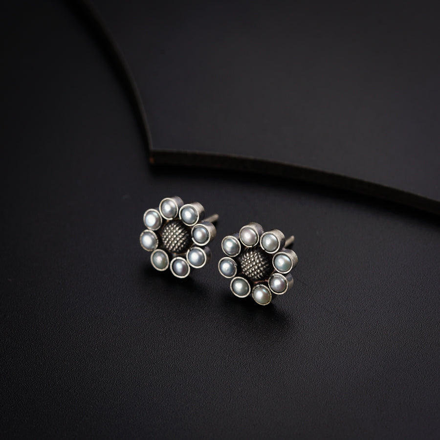 a pair of silver and pearl earrings on a black surface