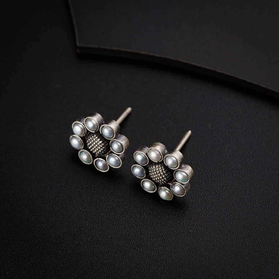 a pair of silver and pearl earrings on a black surface