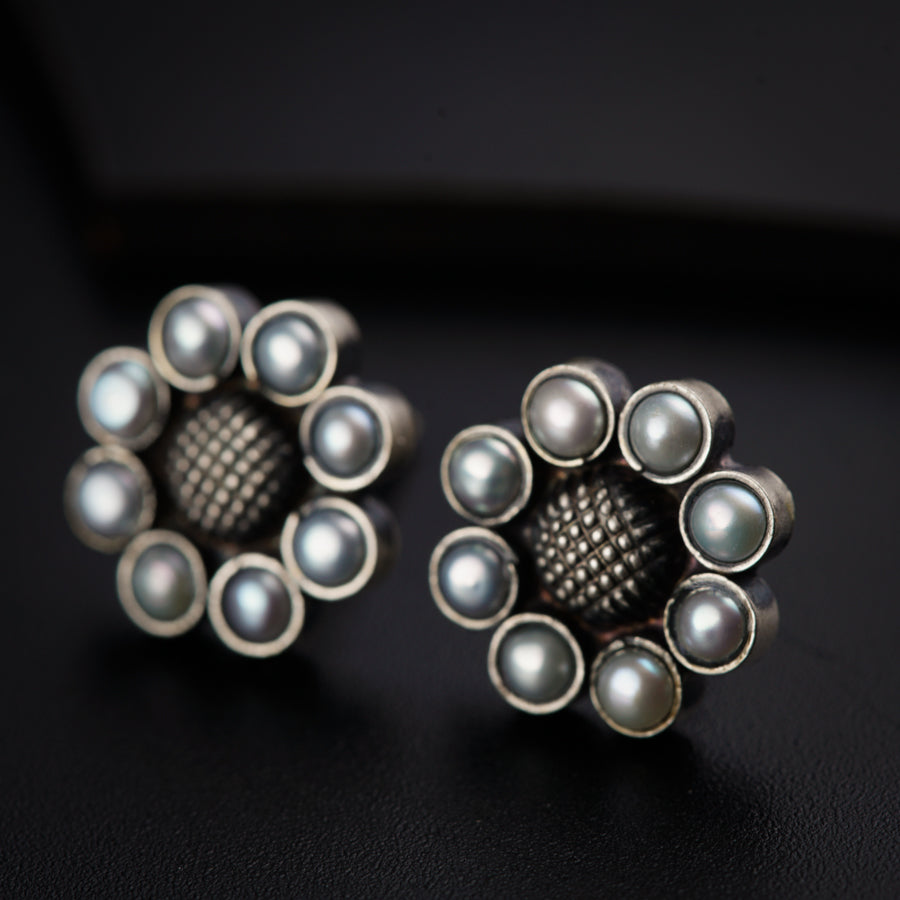 a pair of silver and pearl earrings on a black surface