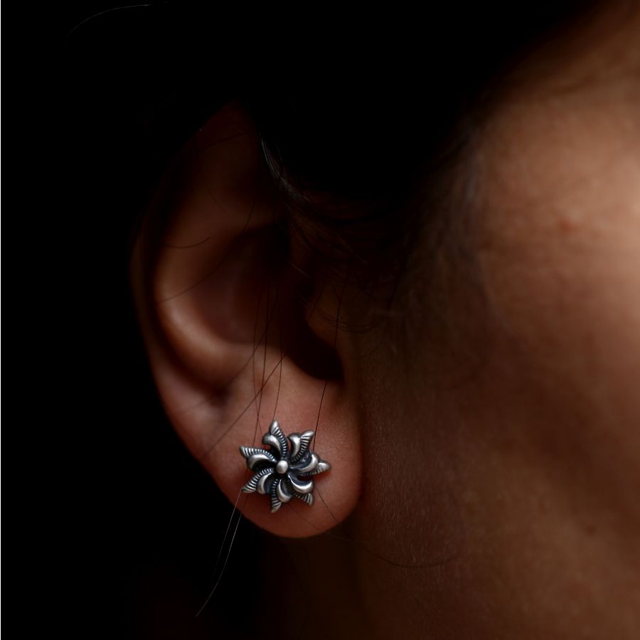 a close up of a person's ear with a silver flower on it