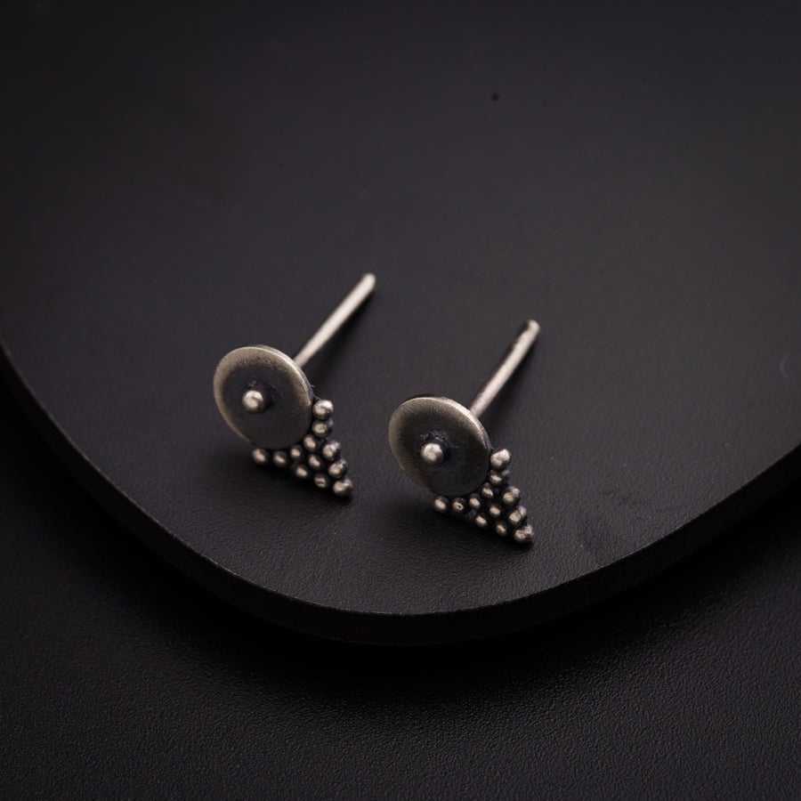 a pair of silver earrings sitting on top of a black surface