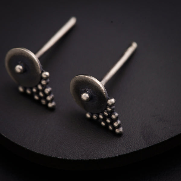 a pair of silver earrings sitting on top of a black surface