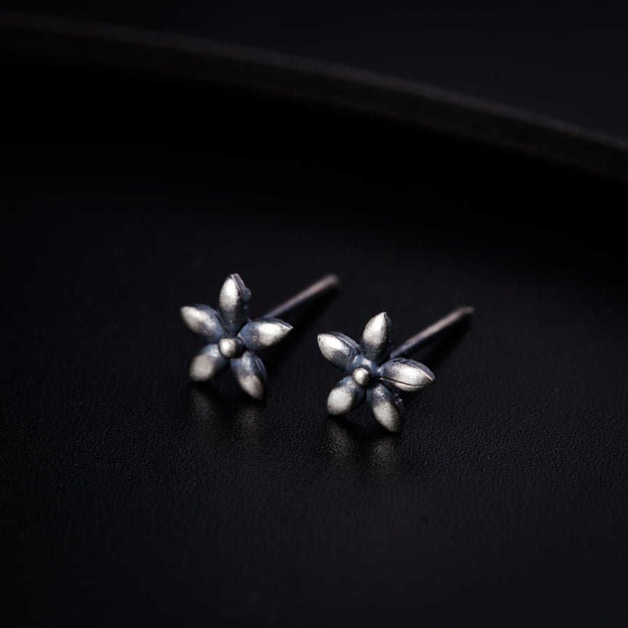 a pair of silver earrings on a black surface