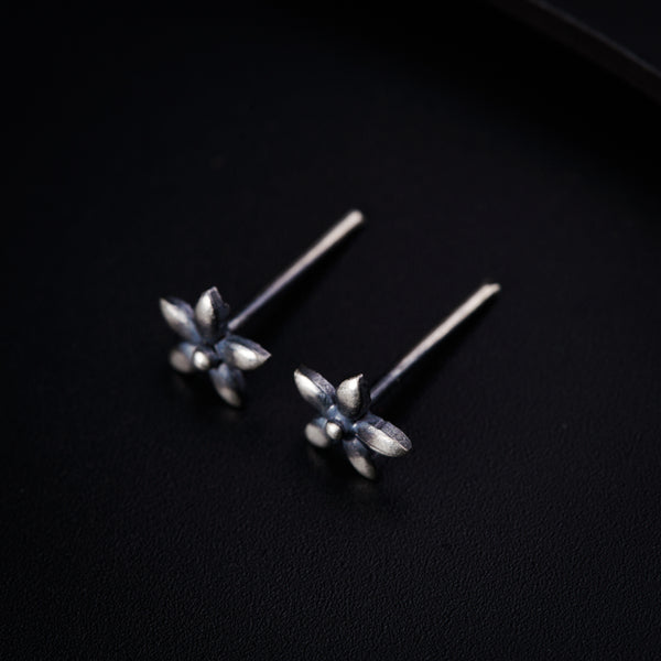 a pair of silver earrings on a black surface
