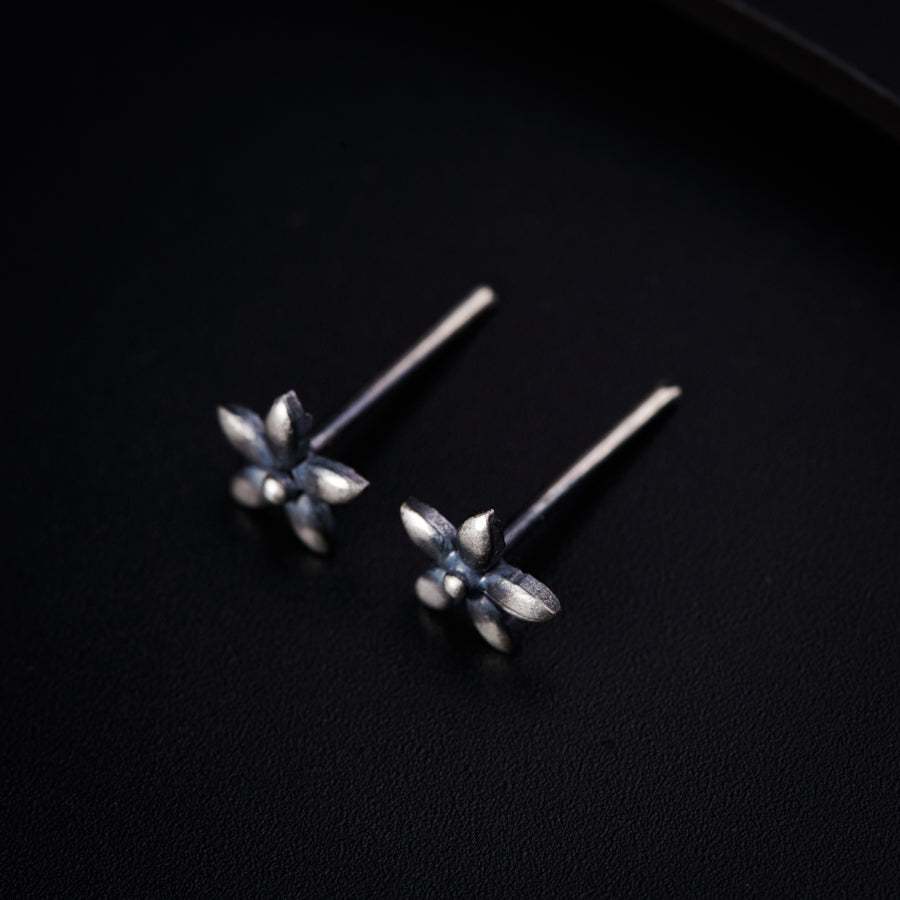 a pair of silver earrings on a black surface