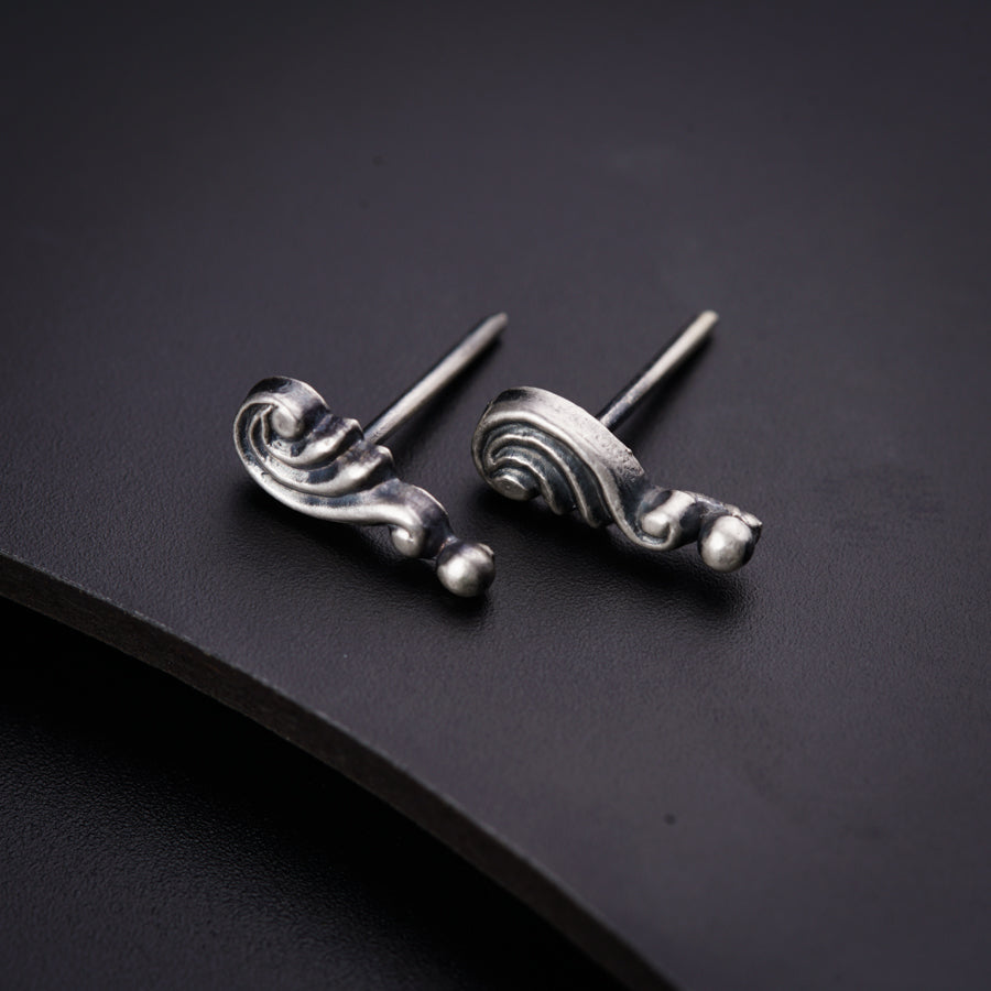 a pair of silver earrings sitting on top of a black surface