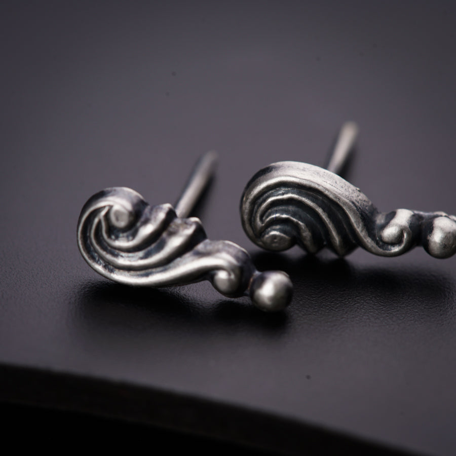 a pair of silver earrings sitting on top of a table