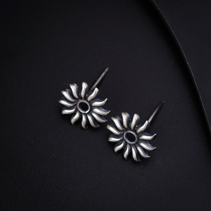 a pair of sunflower earrings on a black background