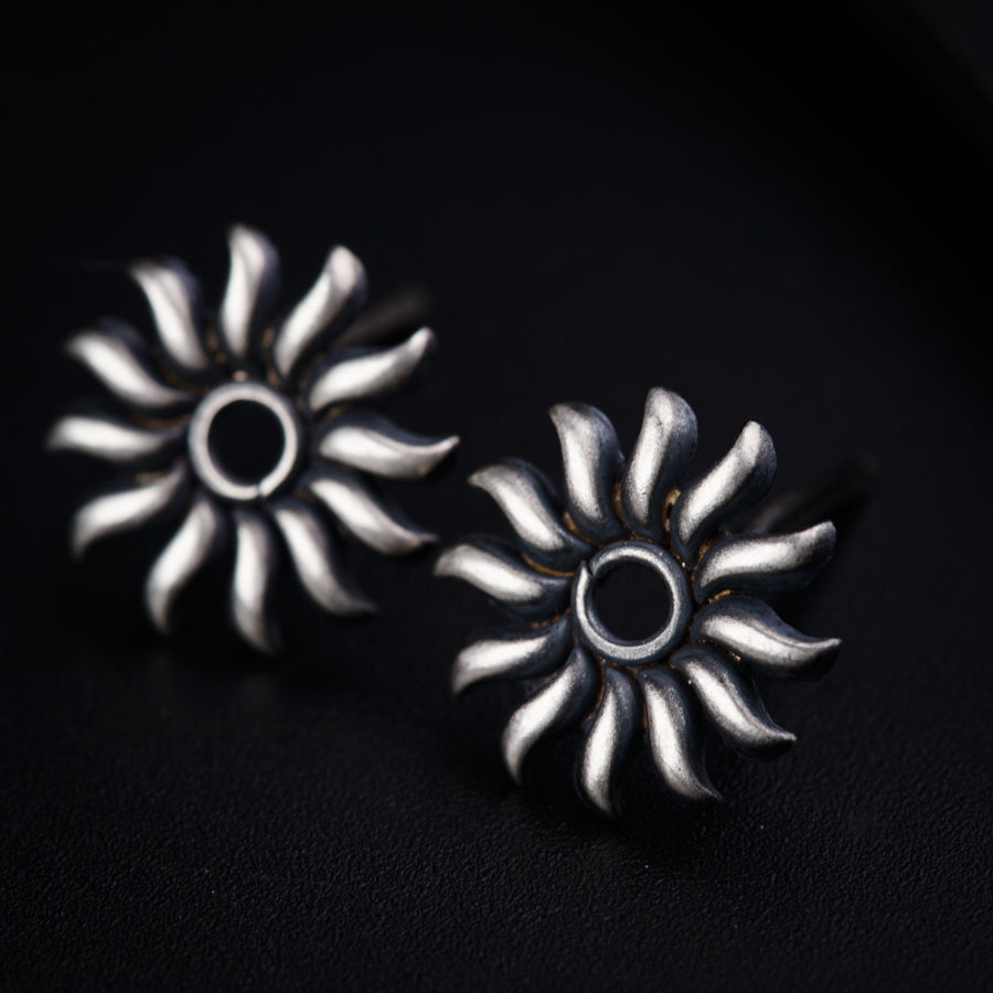 a pair of silver earrings sitting on top of a black surface