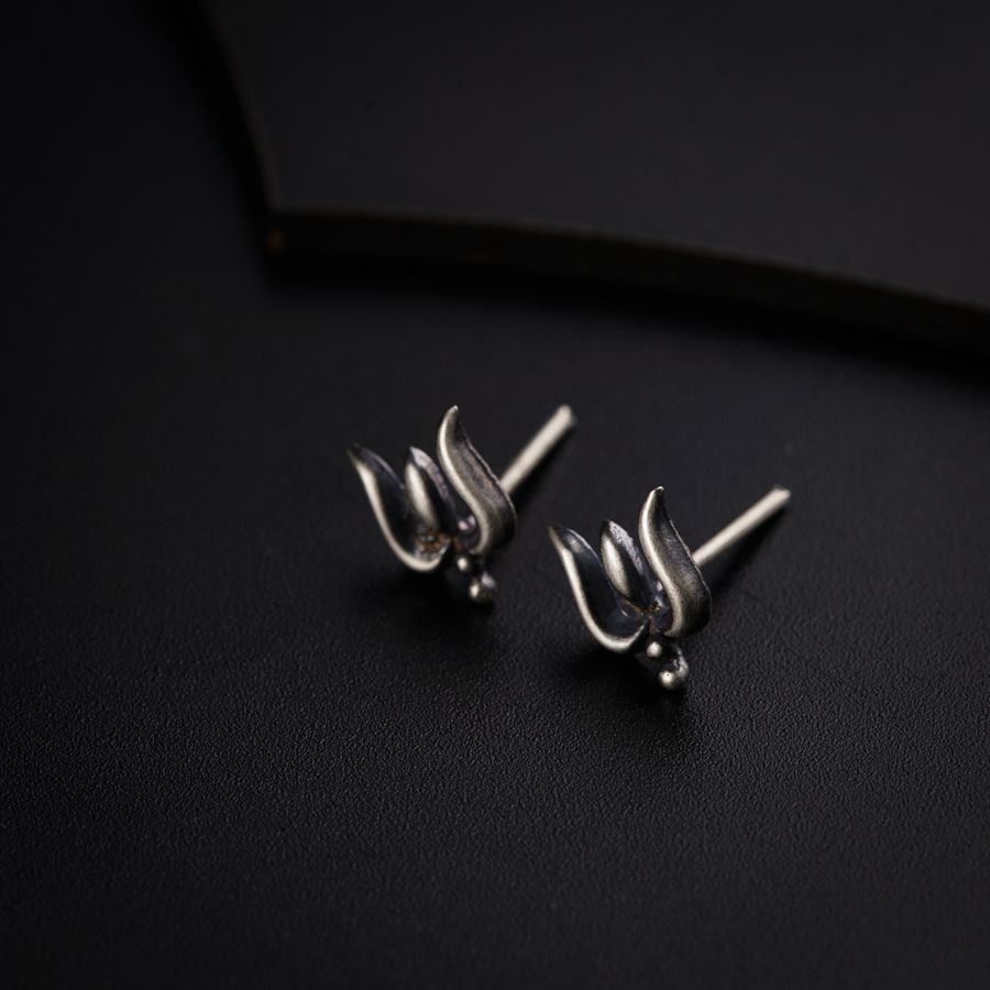 a pair of silver earrings sitting on top of a black surface