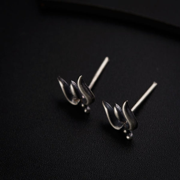 a pair of silver earrings sitting on top of a black surface
