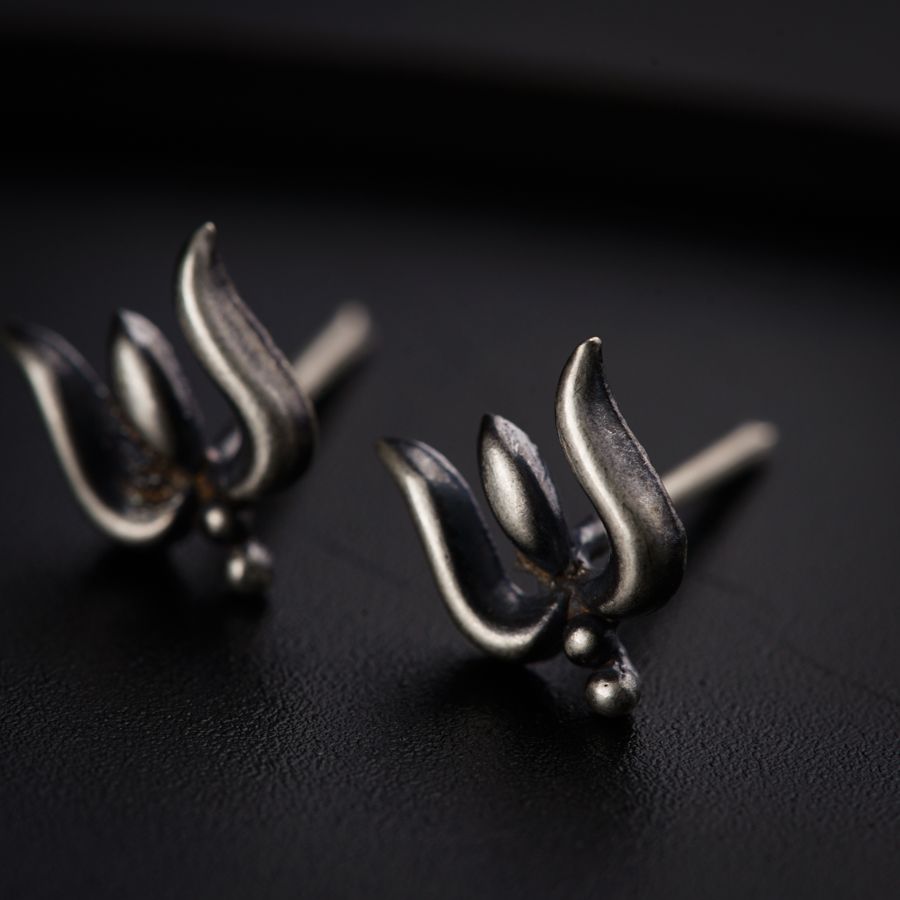 a pair of silver earrings sitting on top of a black surface