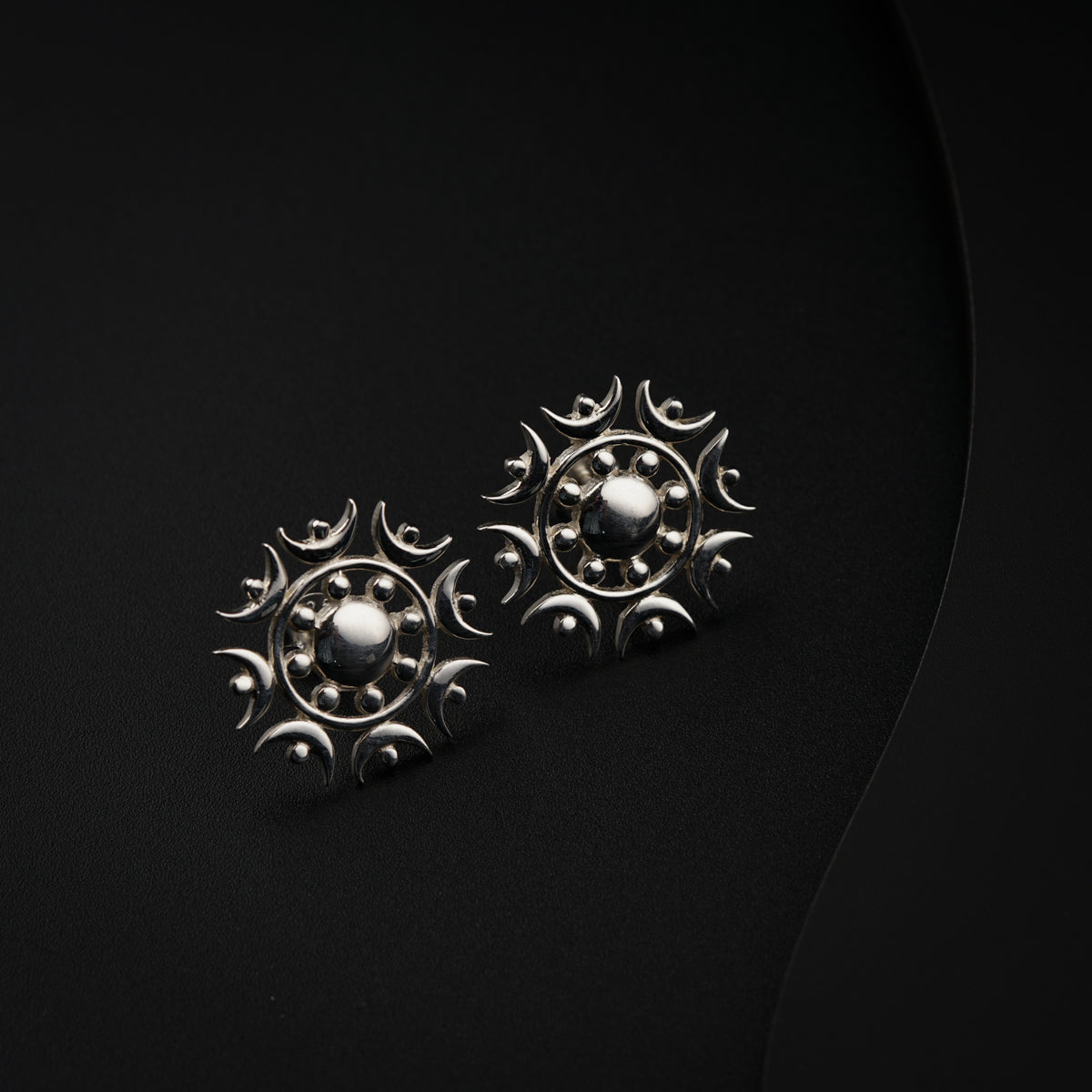 a pair of silver earrings sitting on top of a black surface