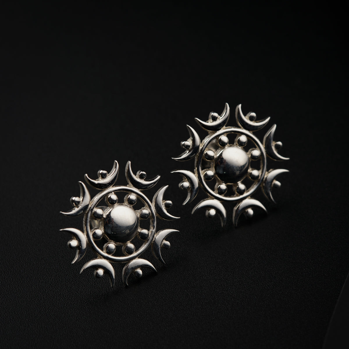 a pair of silver earrings on a black background