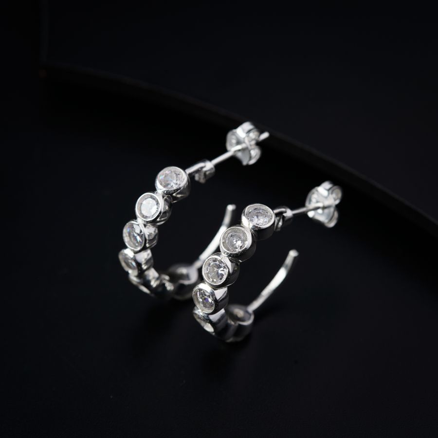 a pair of silver hoop earrings on a black surface