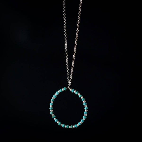 a blue beaded necklace with a circle on a chain