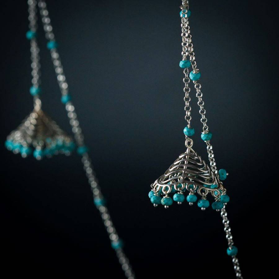 a pair of silver bells hanging from a chain