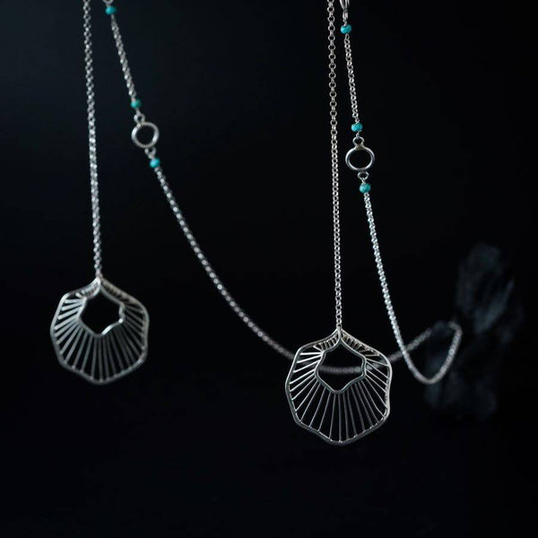 a close up of a pair of silver necklaces