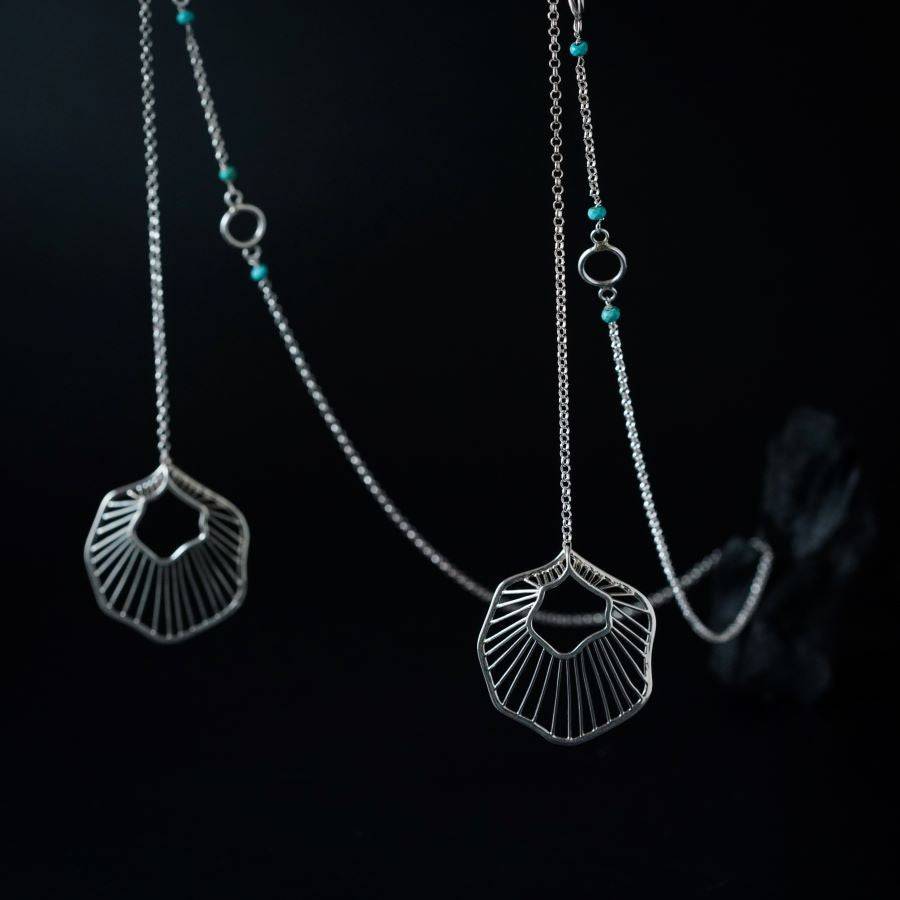 a close up of a pair of silver necklaces