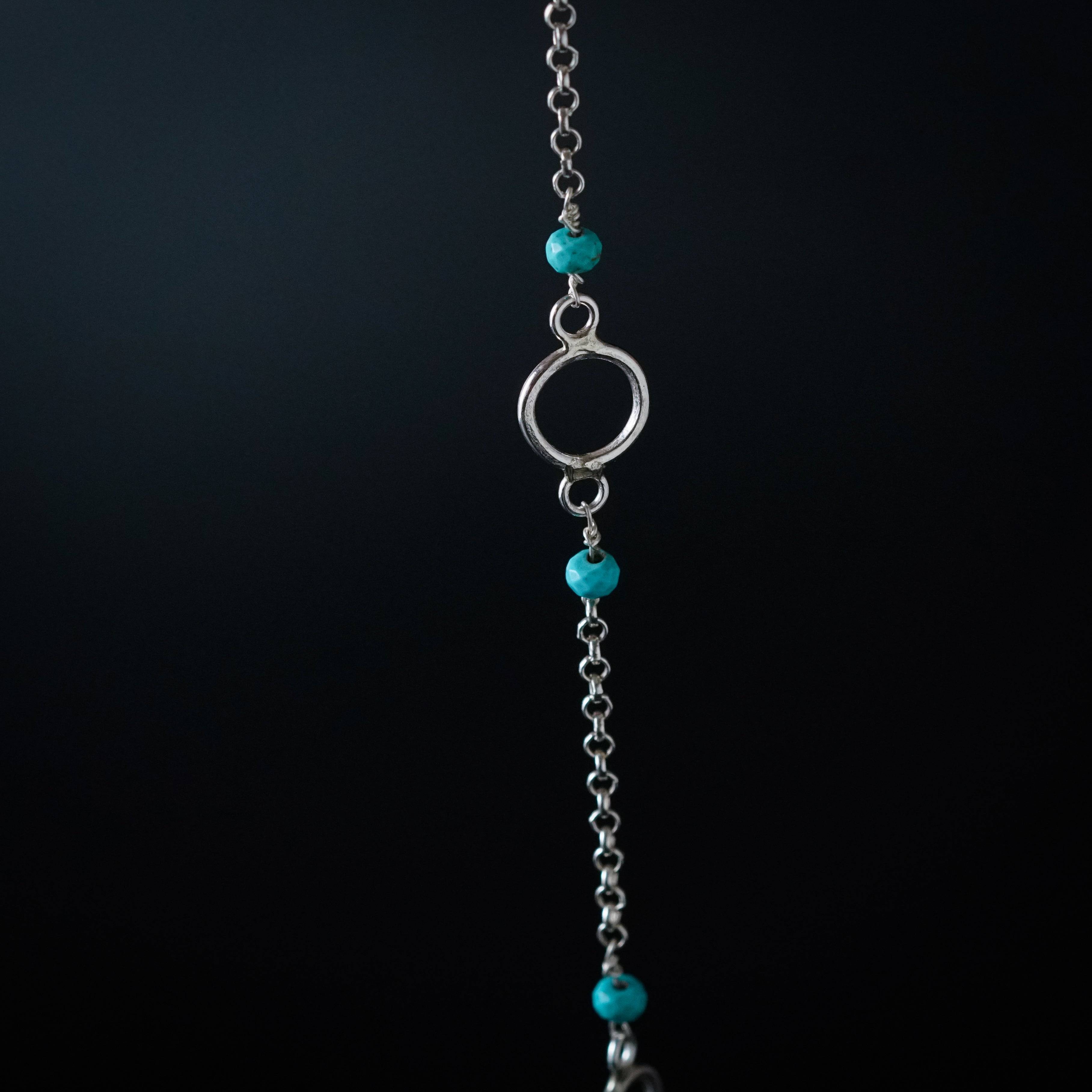 a silver chain with turquoise beads hanging from it