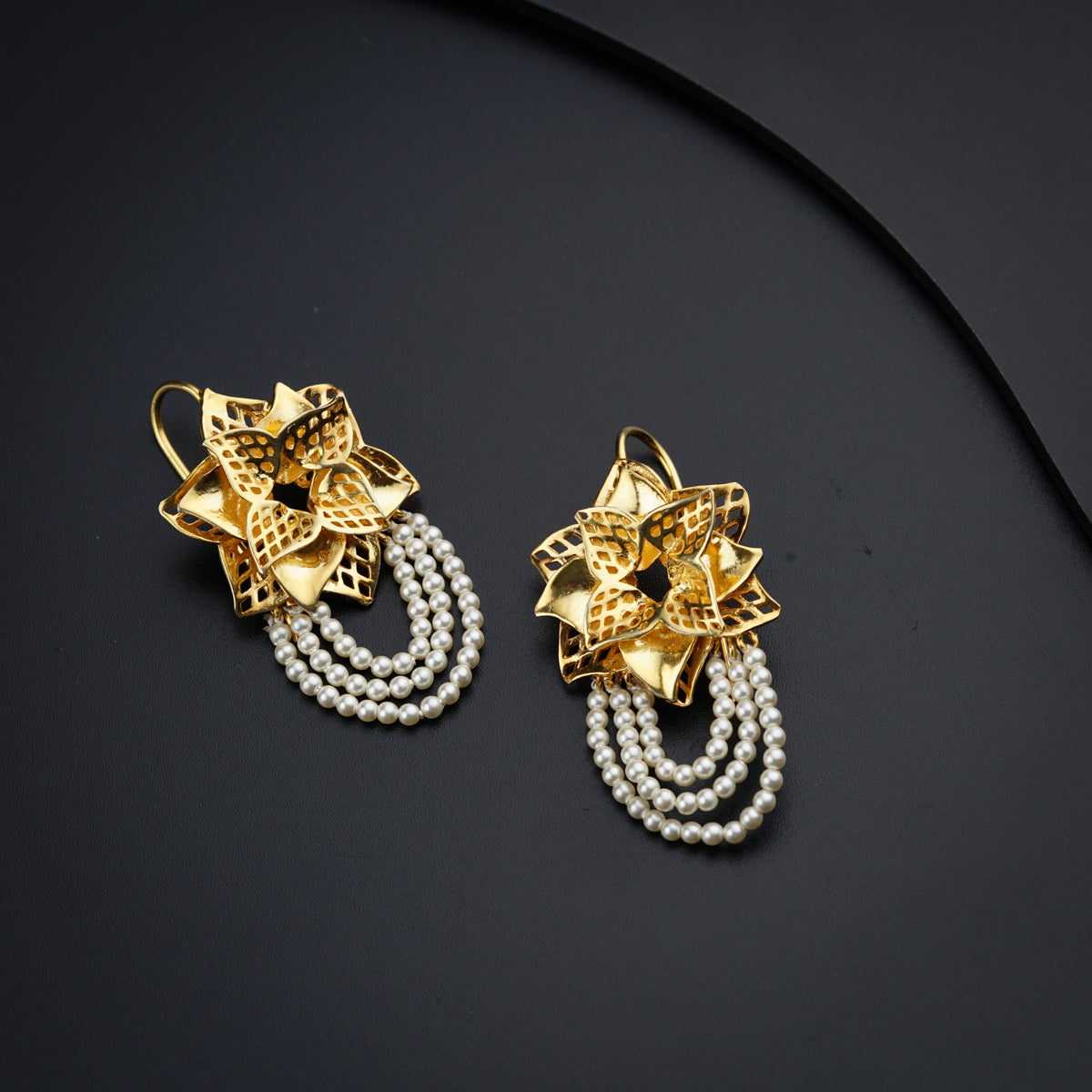 a pair of earrings with pearls on a black surface