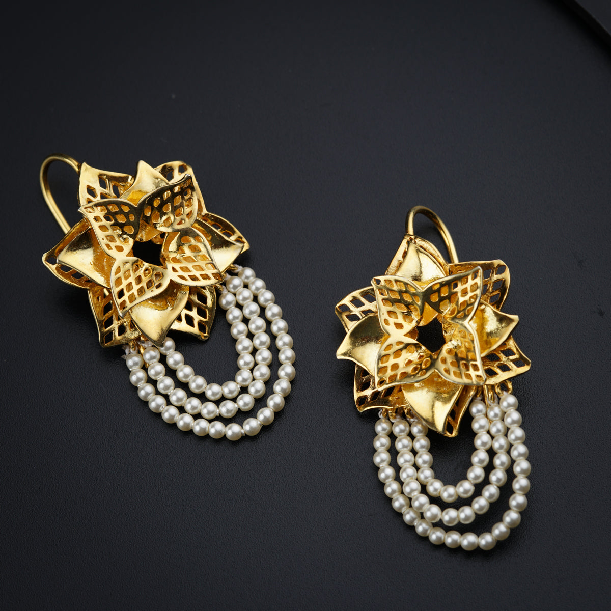 a pair of earrings with pearls on a black surface