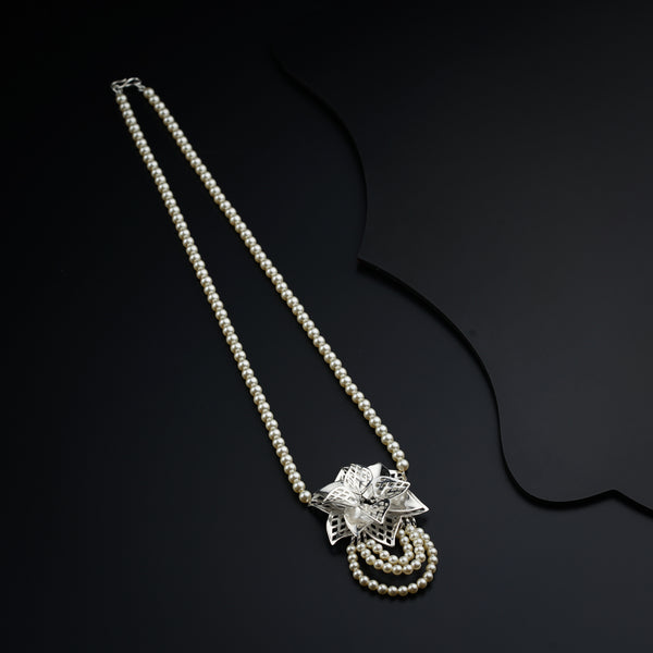 a white pearl necklace with a silver flower on it