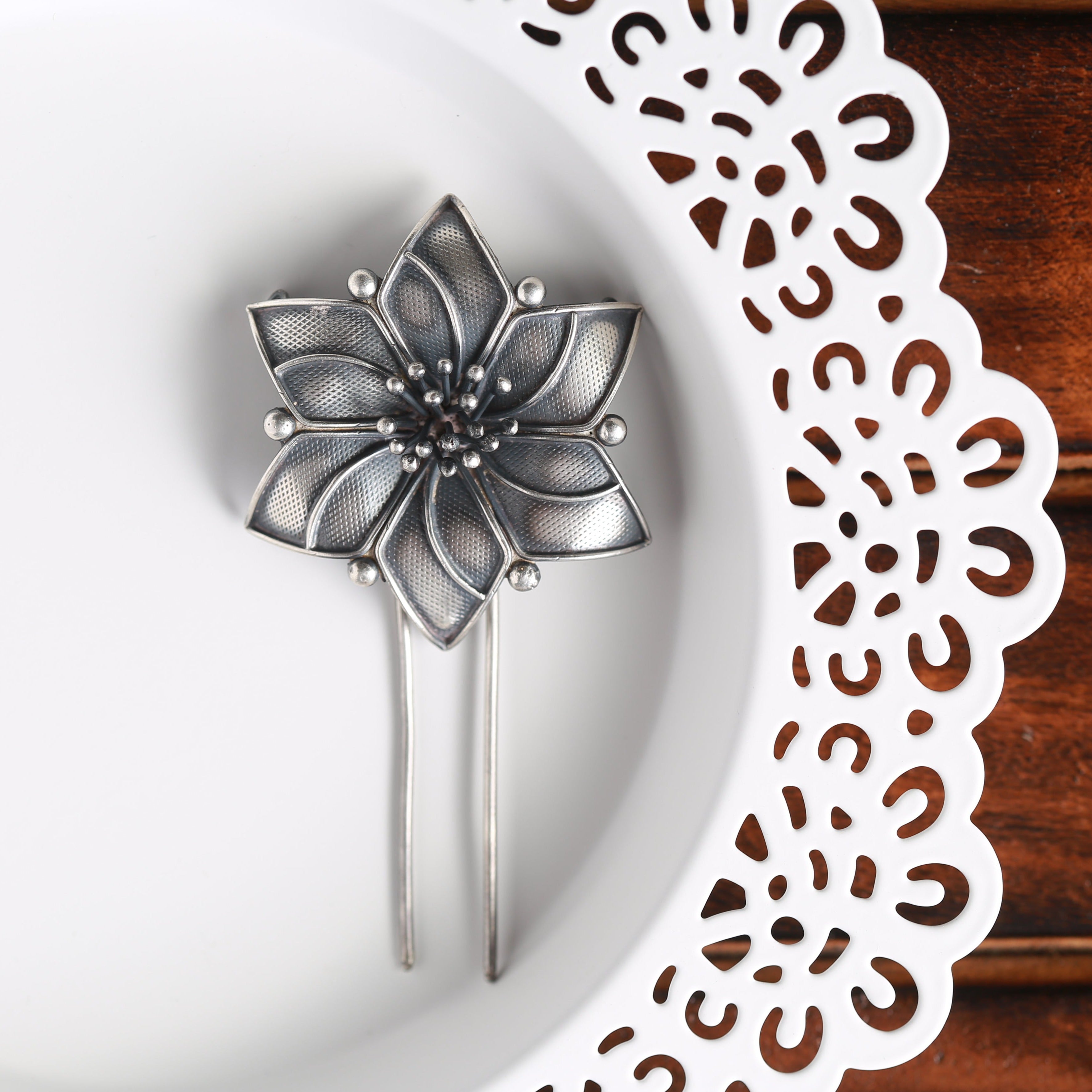 a silver flower pin sitting on top of a white plate