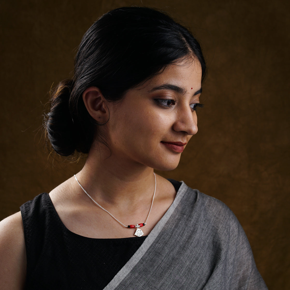 a woman wearing a necklace and a black top