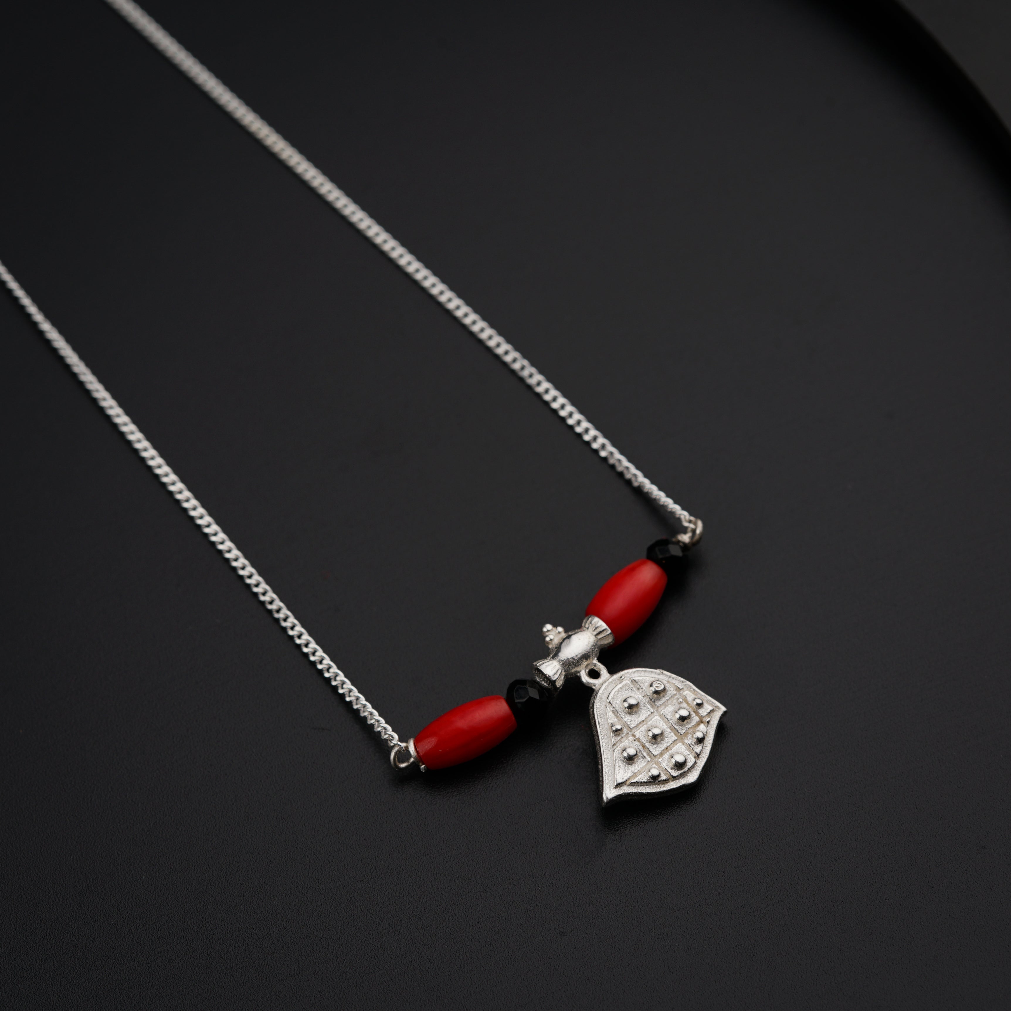 a necklace with a red bead and a silver heart