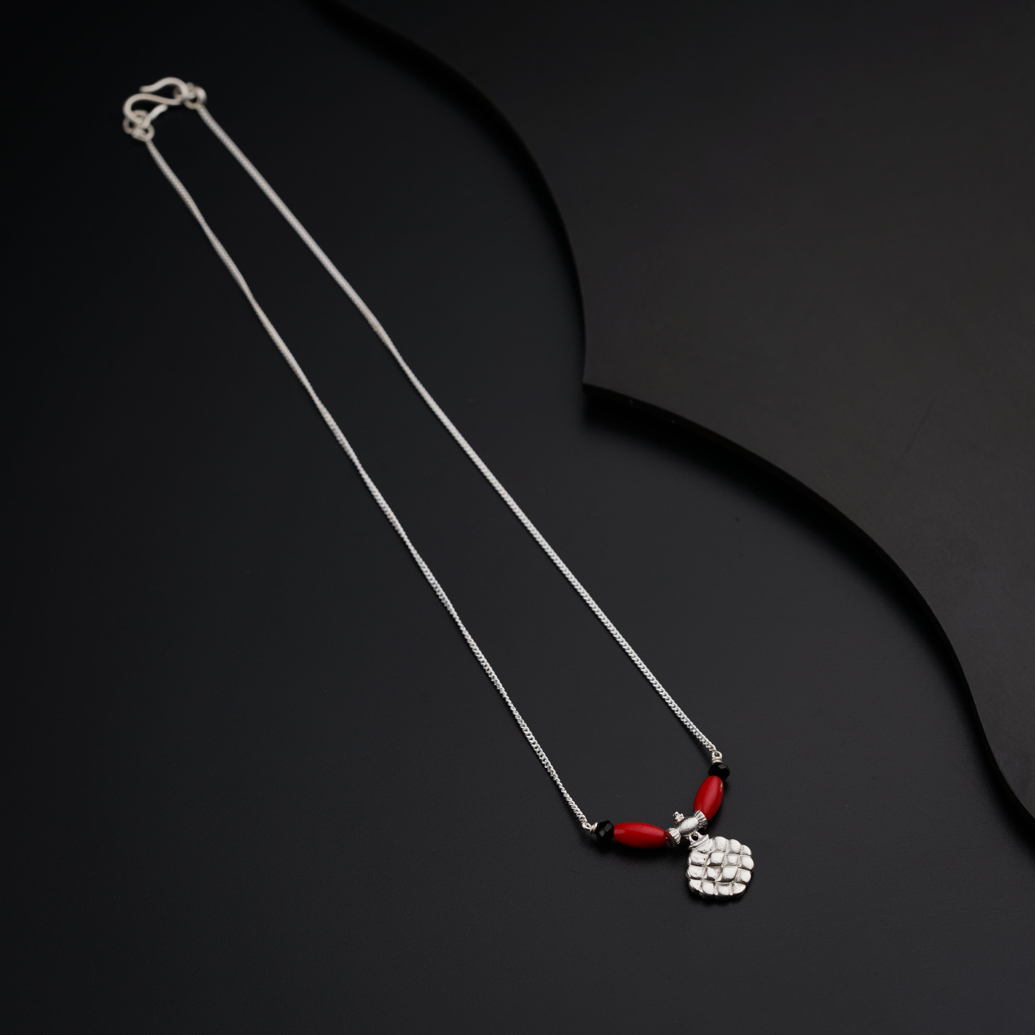 a necklace with a red bead hanging from it