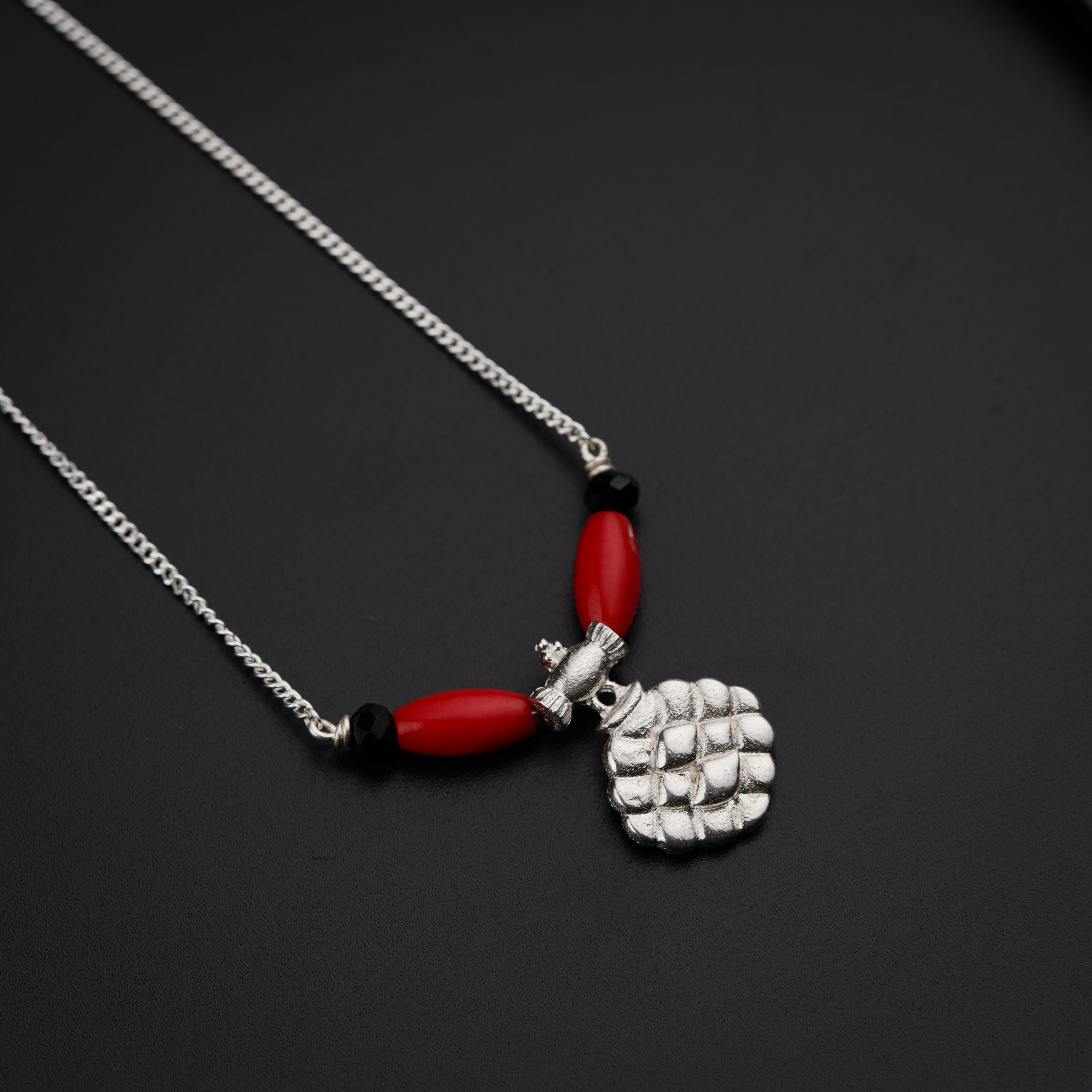 a necklace with a red bead and a silver chain