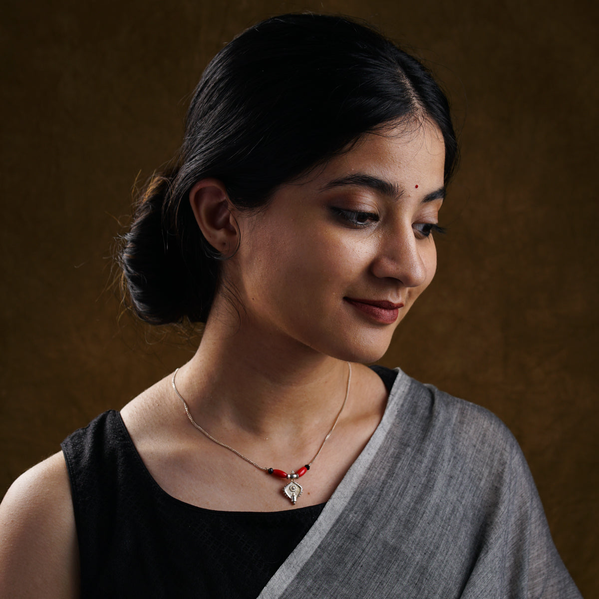 a woman wearing a necklace with a red bead