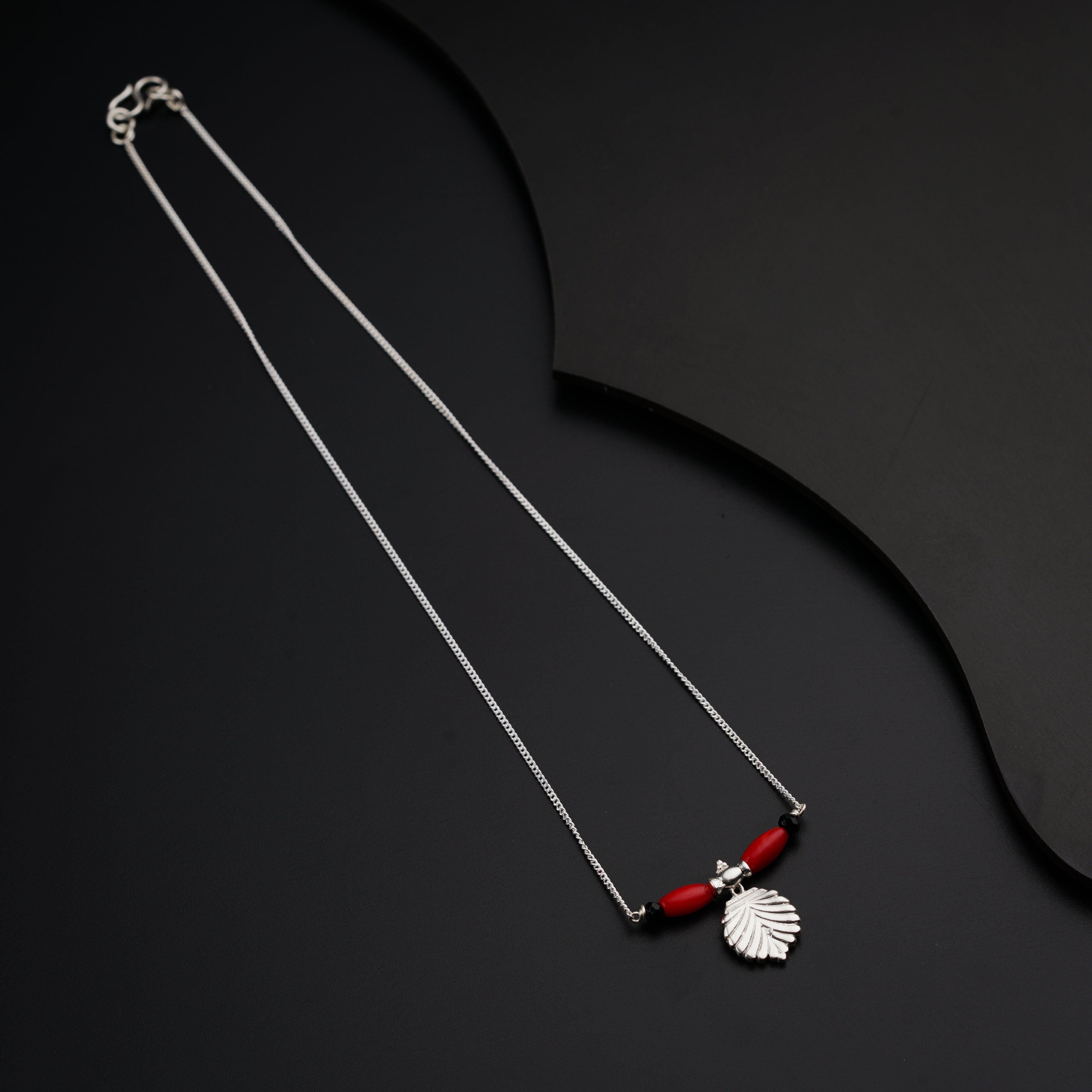 a necklace with a red bead hanging from it