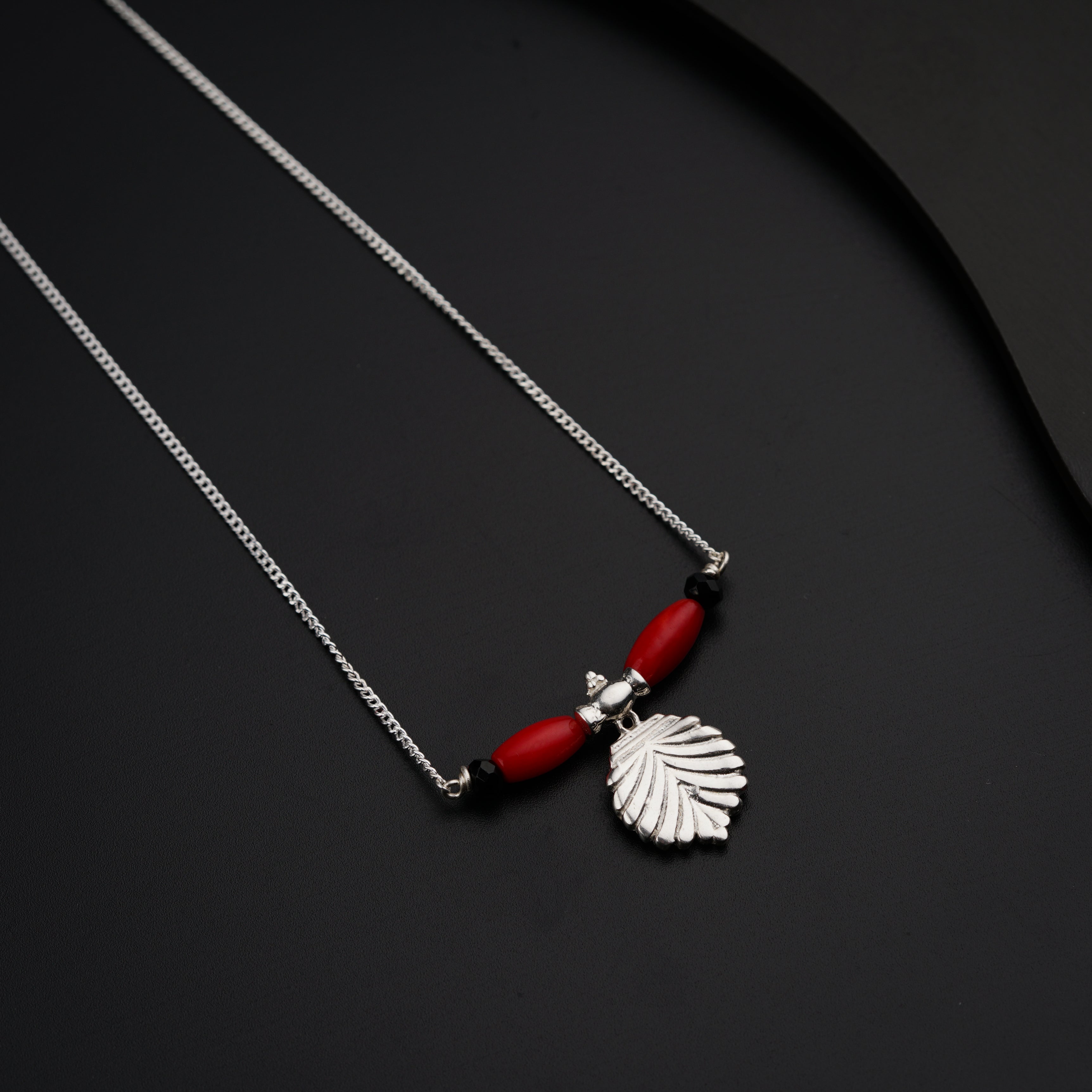 a necklace with a red bead hanging from it