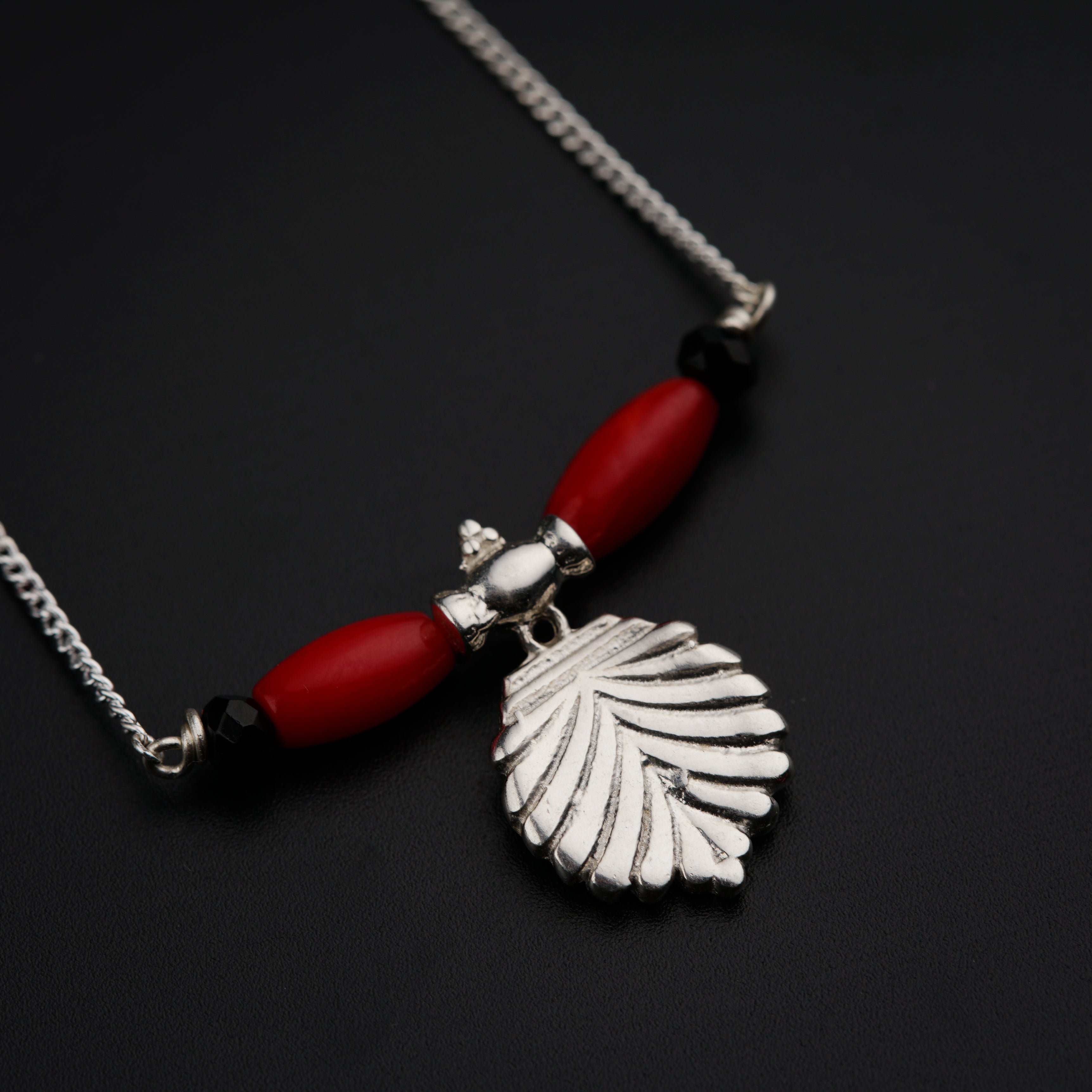 a red and silver necklace with a leaf charm