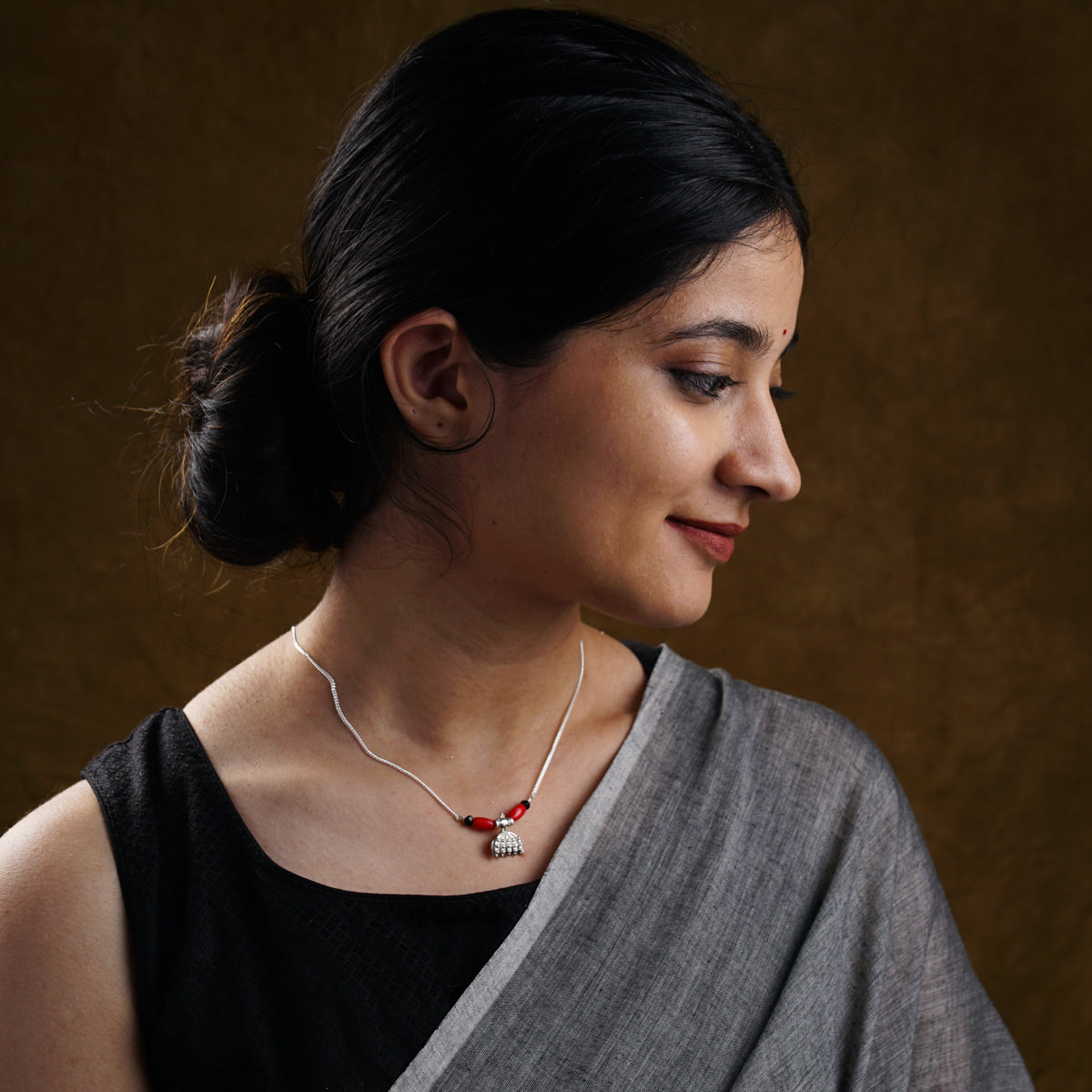 a woman wearing a necklace with a red bead