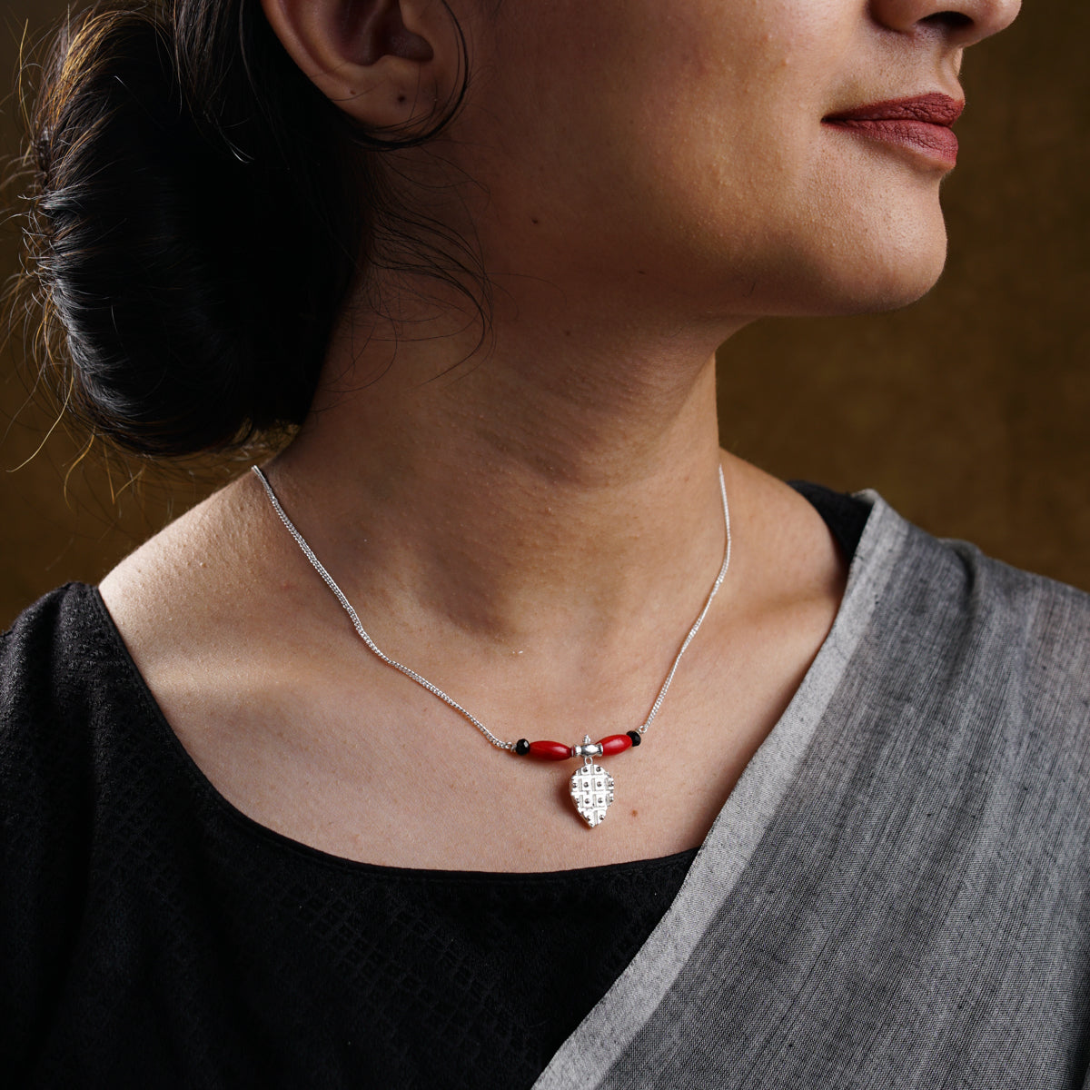 a woman wearing a necklace with a red and white bead