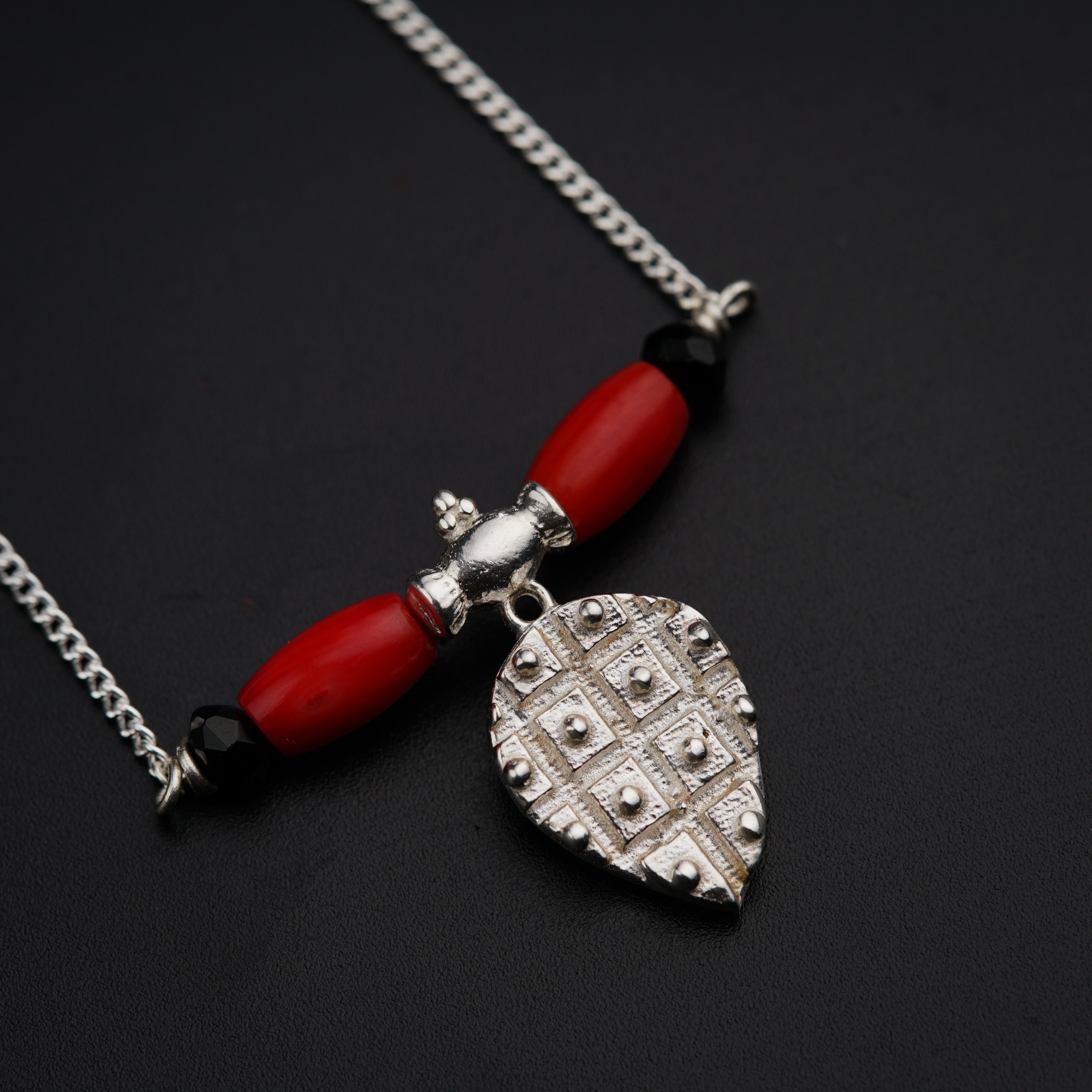 a necklace with a red bead and a heart shaped pendant