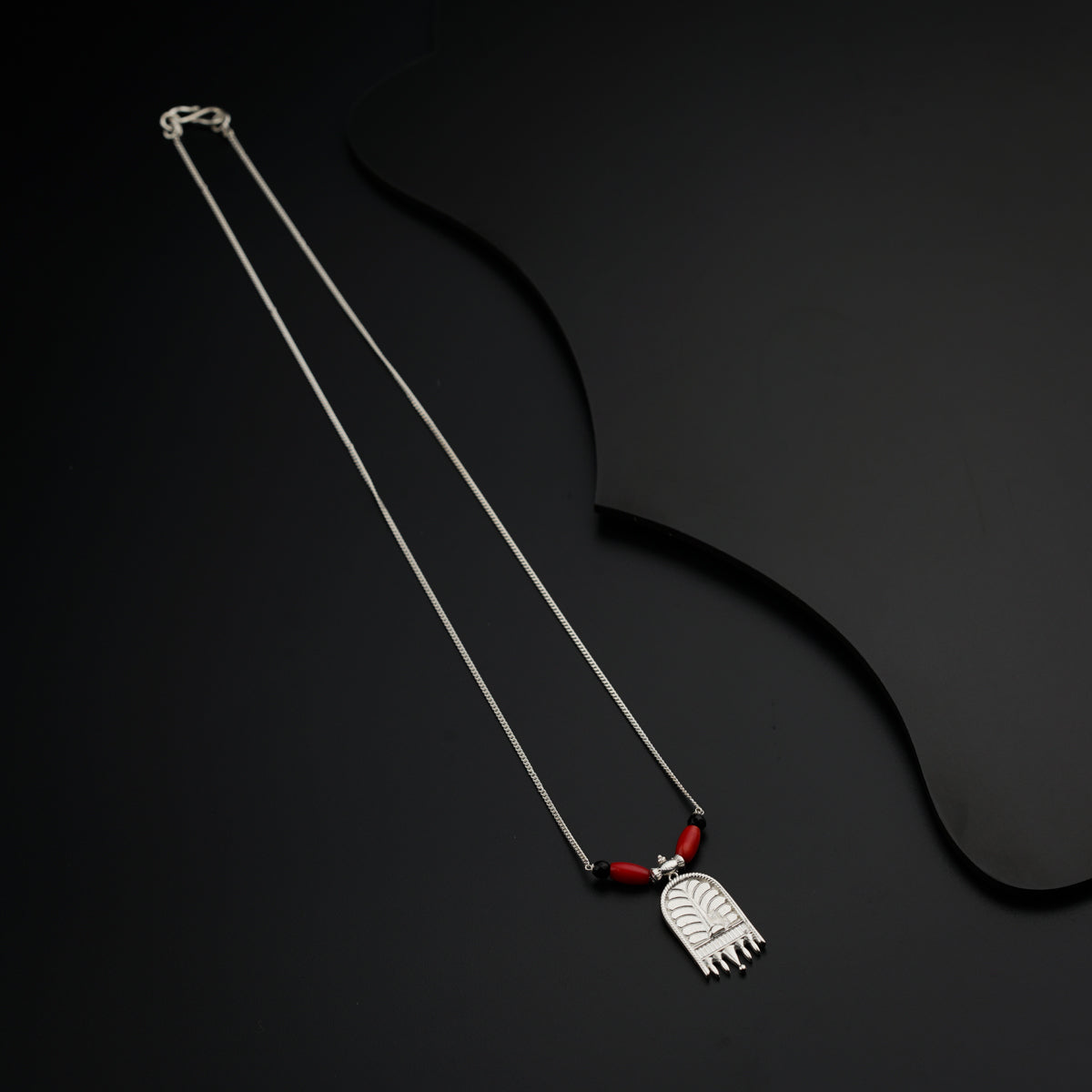 a pair of necklaces with a red bead hanging from it