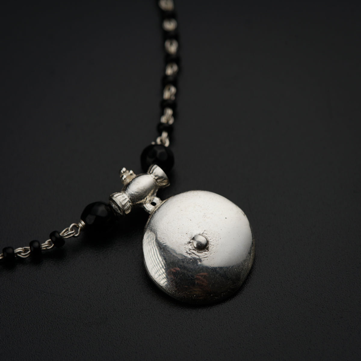 a black beaded necklace with a silver ball on it