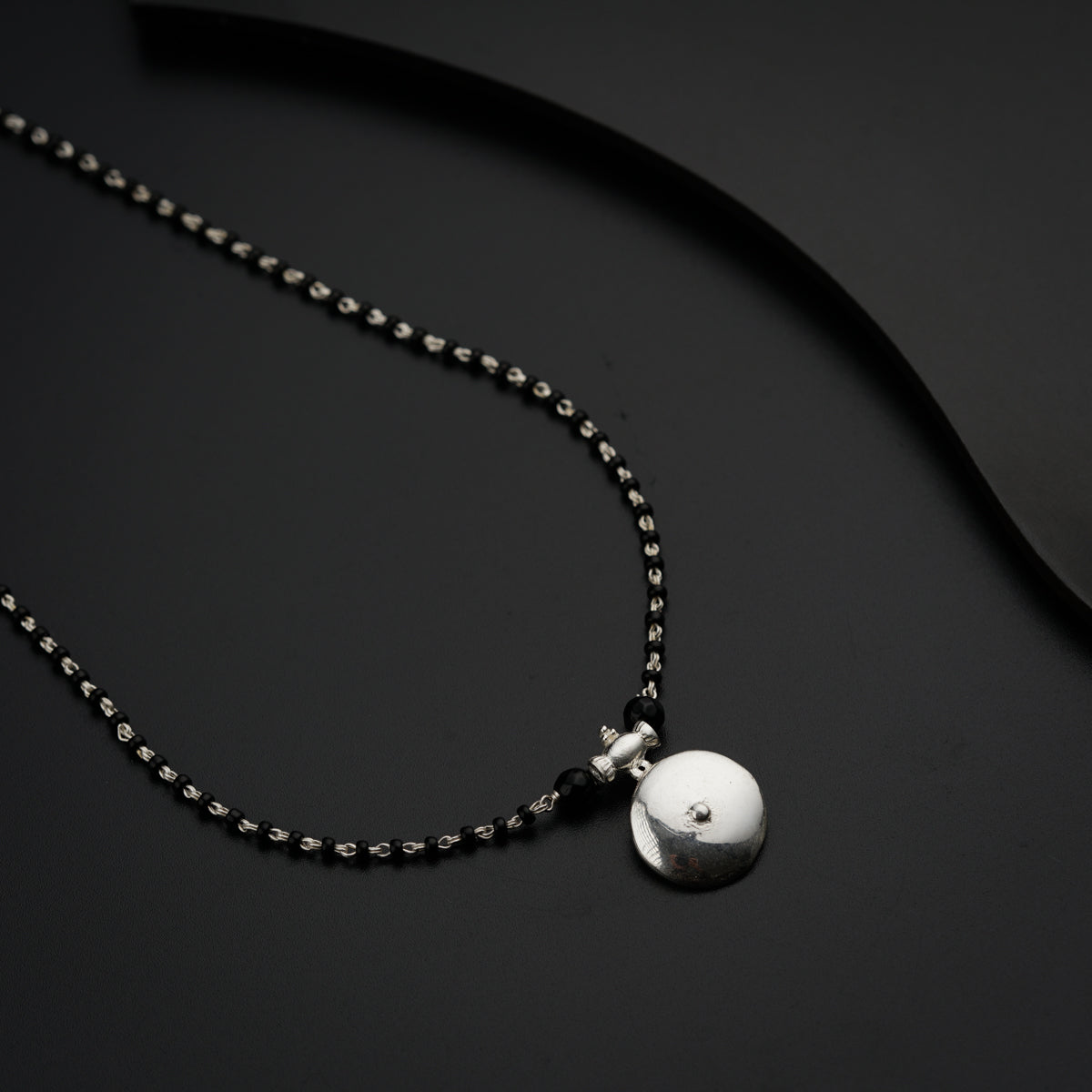 a black necklace with a white ball on it