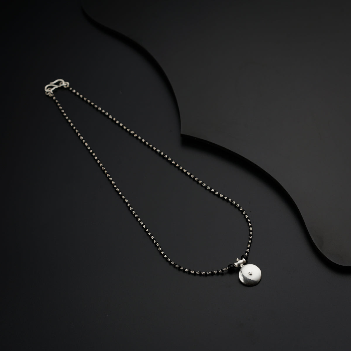 a black and white photo of a necklace on a black surface