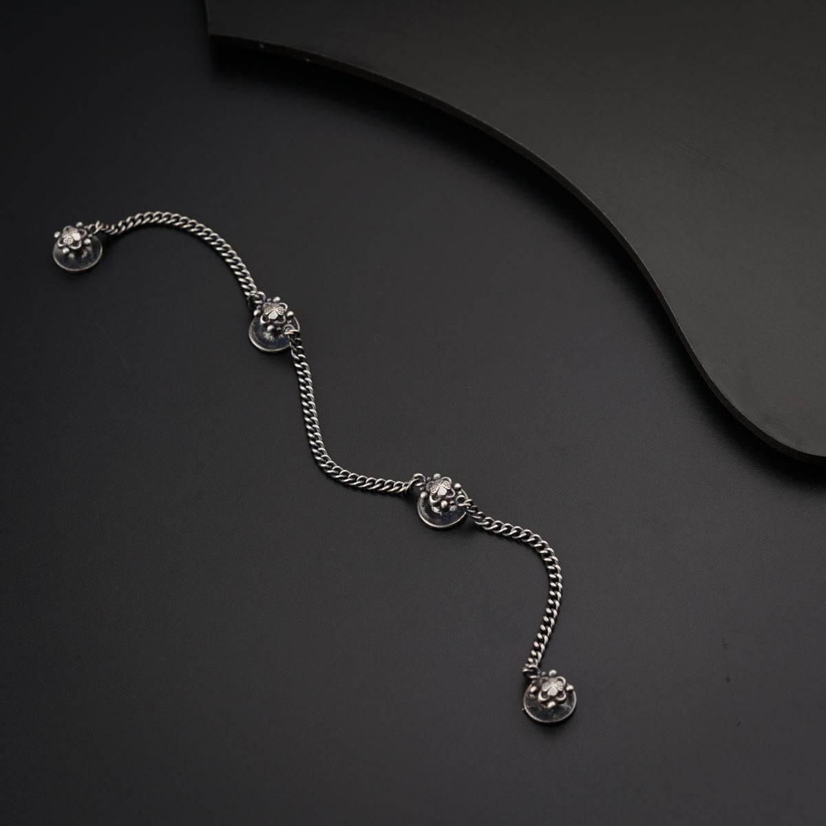a silver bracelet with a chain on a black surface