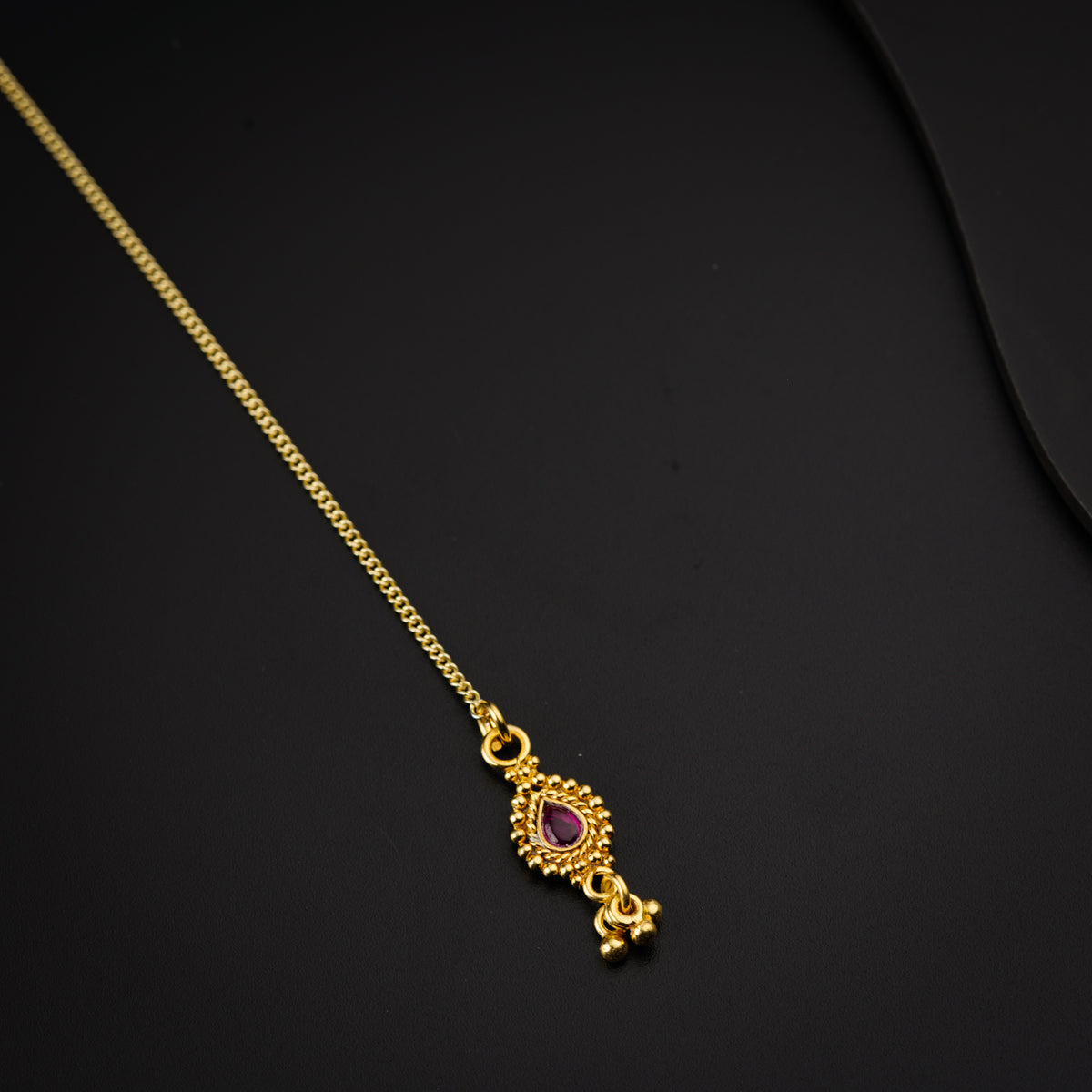 a gold necklace with a pink stone on it
