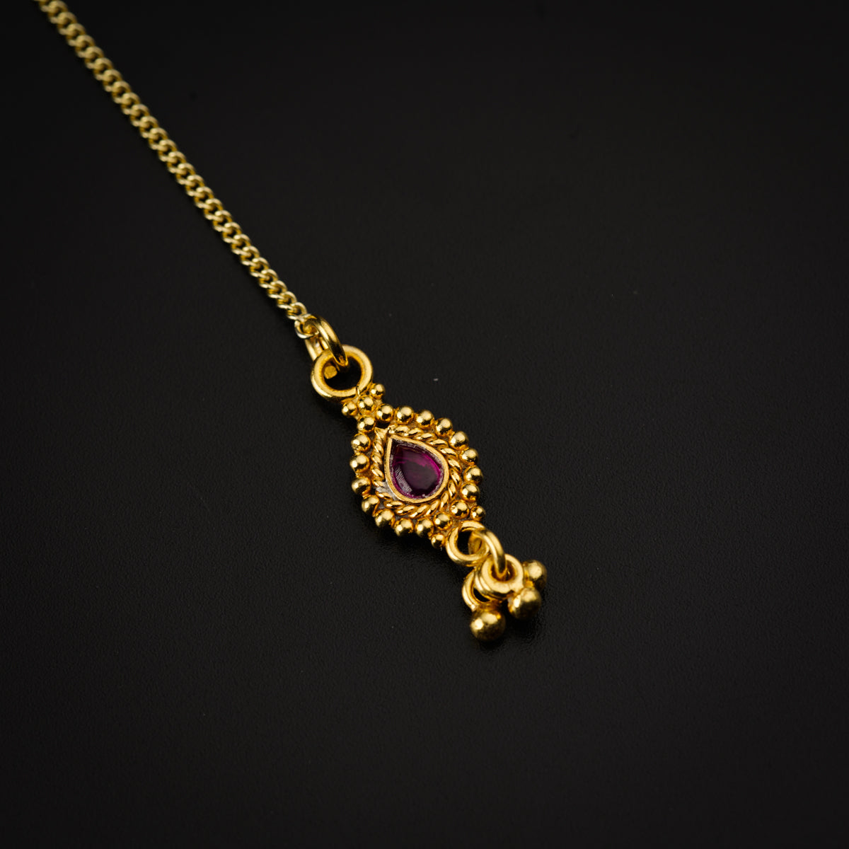 a close up of a gold necklace on a black surface